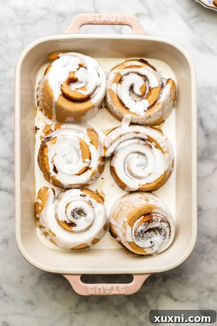 Vegan heavy cream poured over the unbaked cinnamon rolls in a dish.