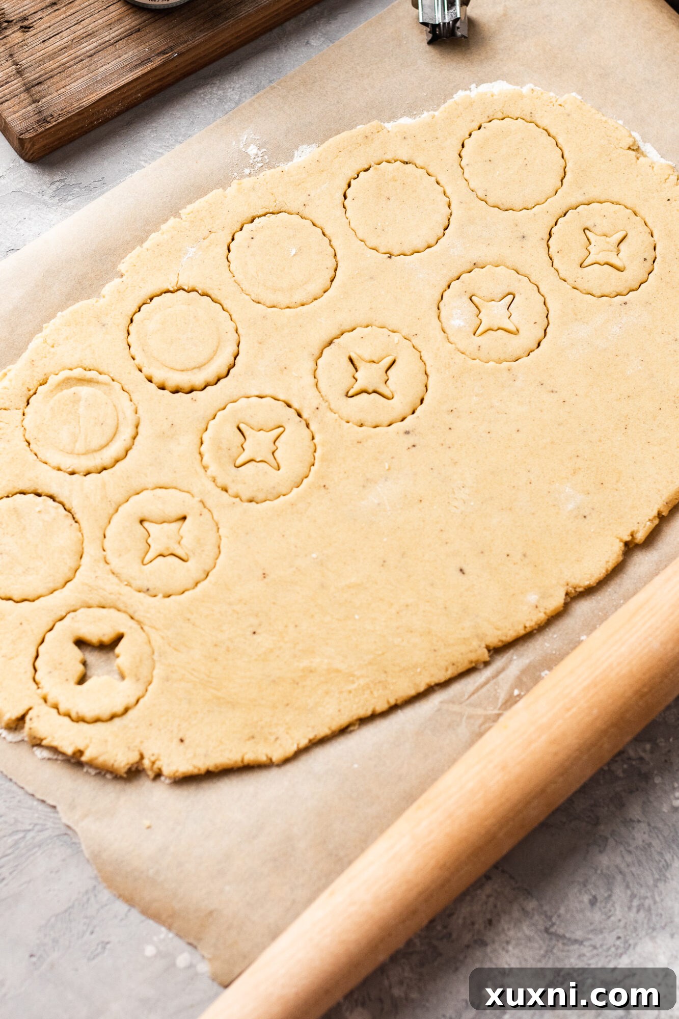 Linzer cookie dough being cut with a Linzer cookie cutter