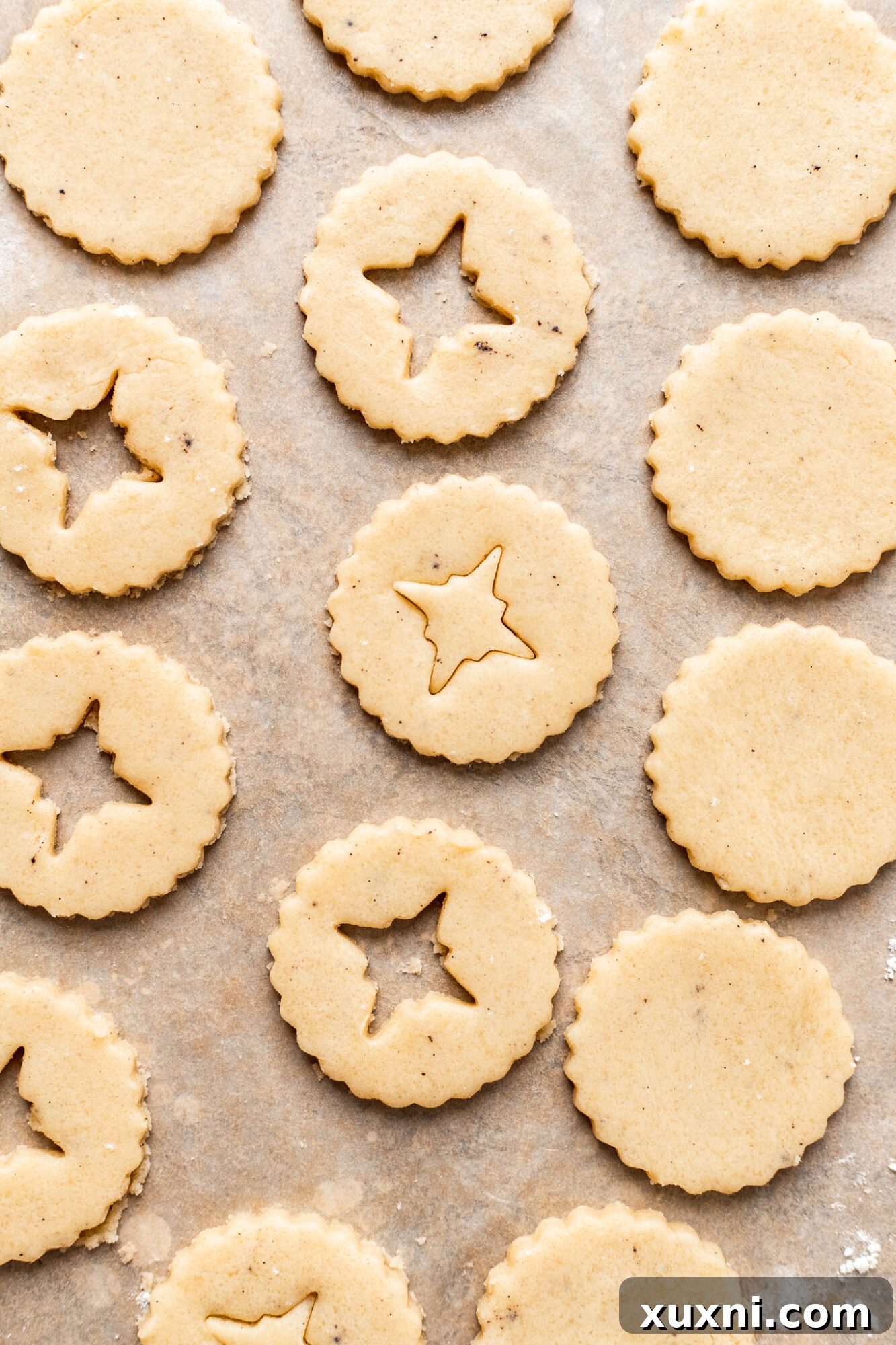 Delicate vegan Linzer cookie cut-outs on parchment paper