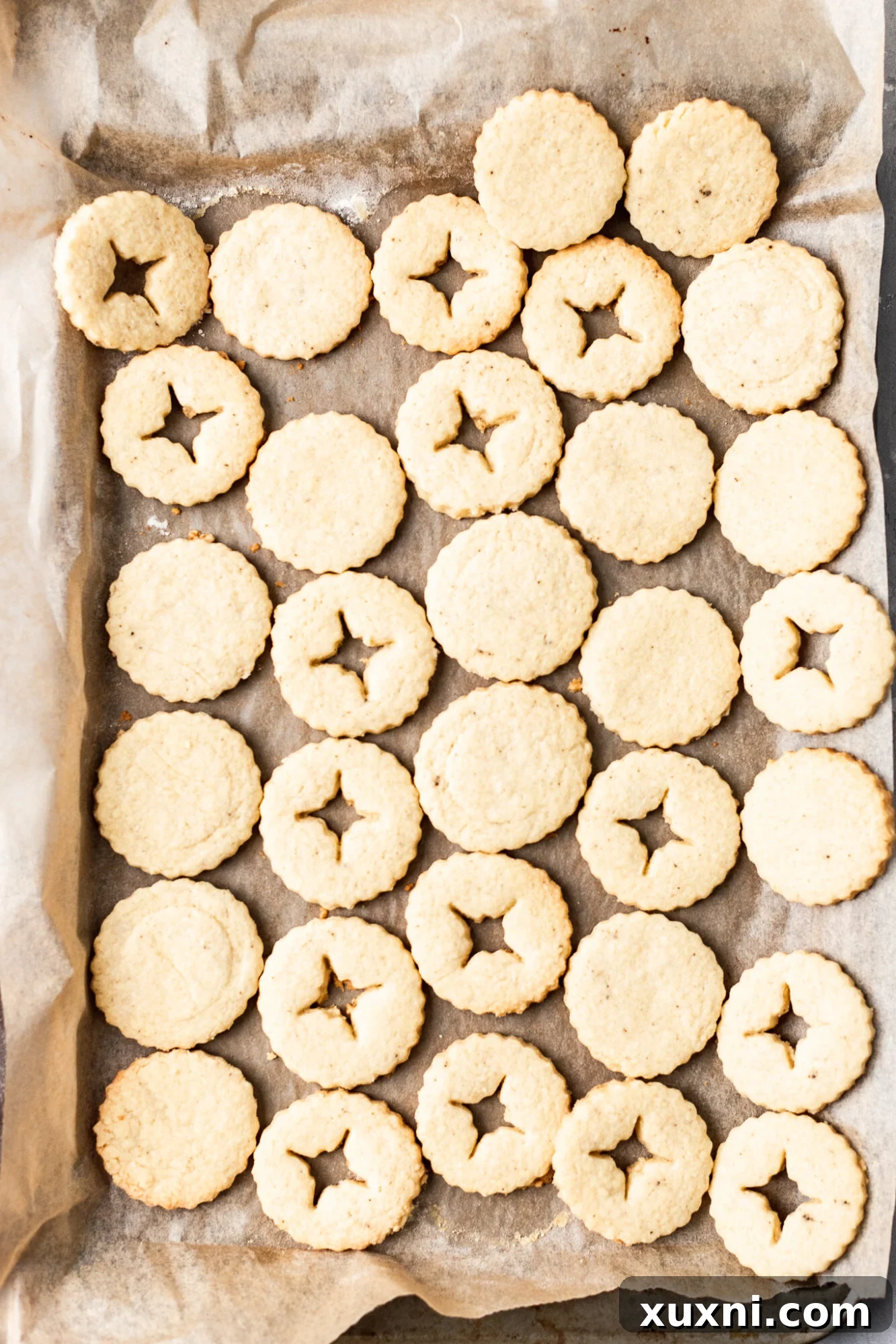 Freshly baked vegan Linzer cookie halves cooling on a rack