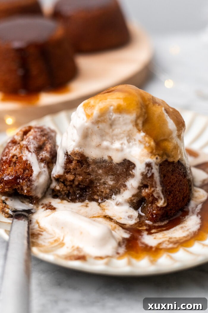 Simply Divine Vegan Sticky Toffee Pudding 14 A close-up of a half-eaten vegan sticky toffee pudding, emphasizing its rich, date-filled interior and the luscious toffee sauce.