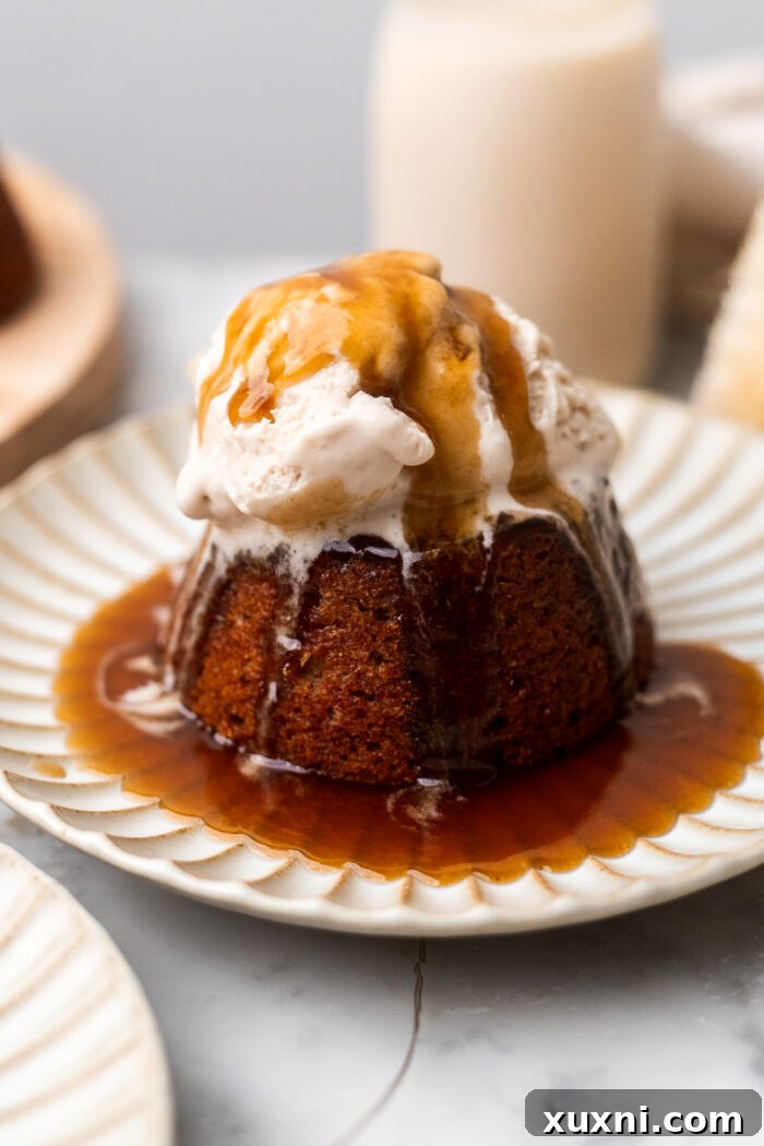Simply Divine Vegan Sticky Toffee Pudding 3 A plate featuring a perfectly portioned vegan sticky toffee pudding, showcasing its rich, dark color and generous toffee sauce glaze.