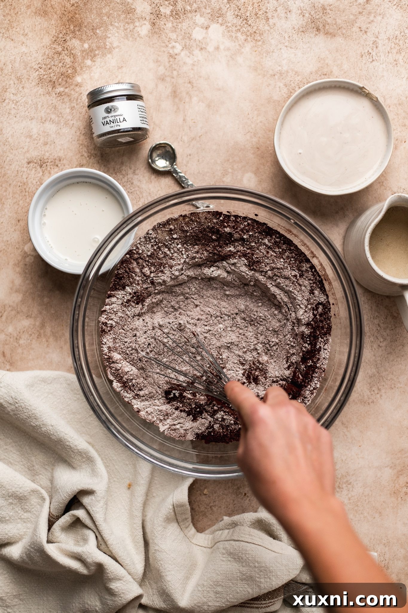 Whisking together flour, cocoa powder, baking powder, and baking soda for vegan chocolate donuts.