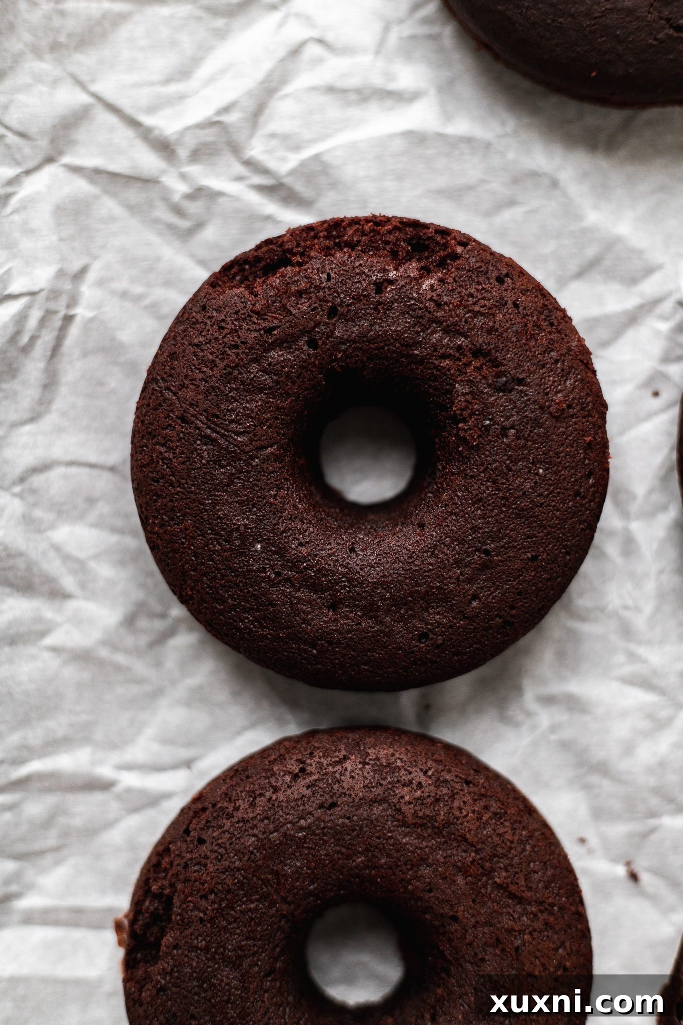 Baked vegan chocolate donuts, golden brown and perfectly puffed, cooling in the pan.