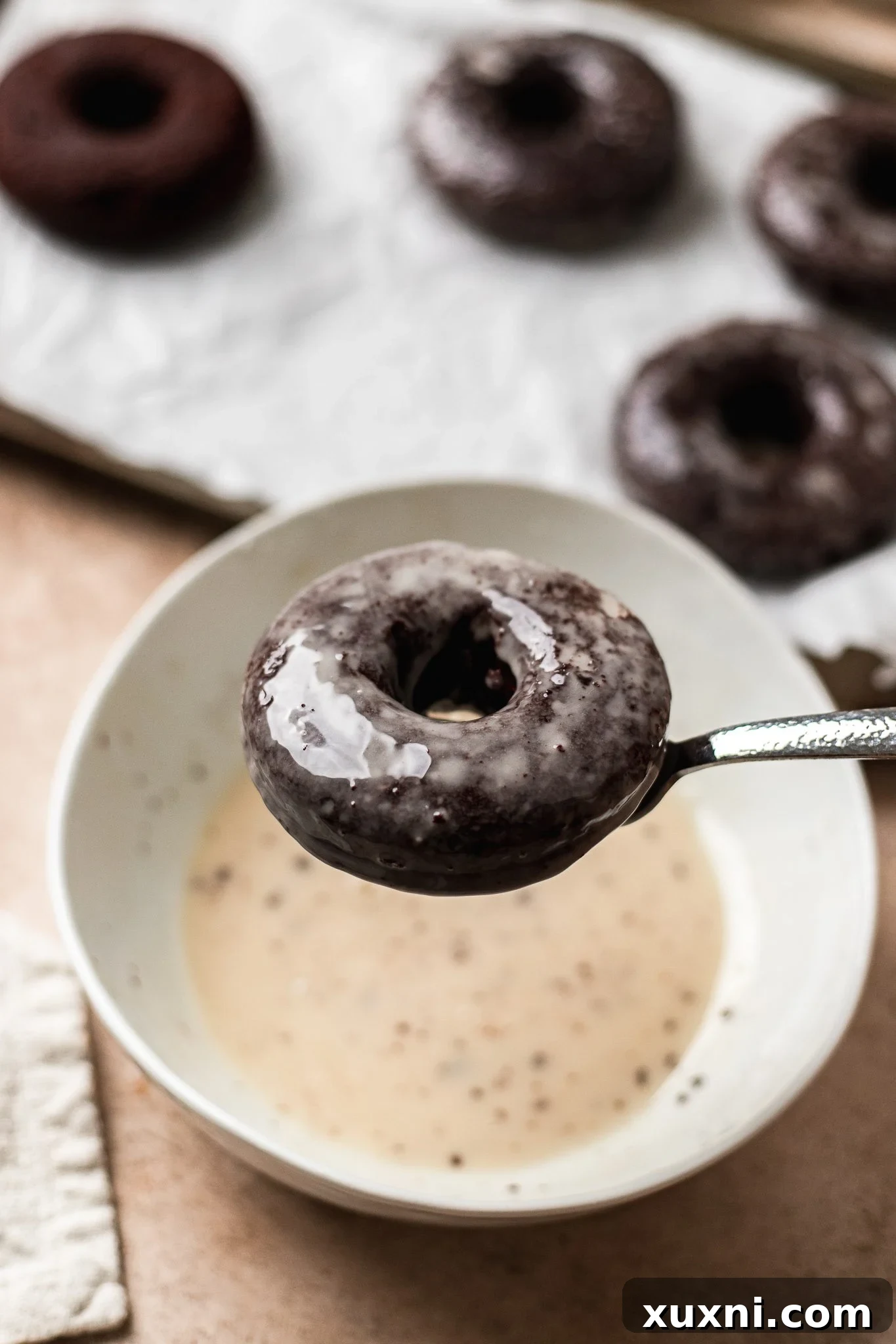 Freshly glazed vegan chocolate donuts on a wire rack, with the glaze setting.