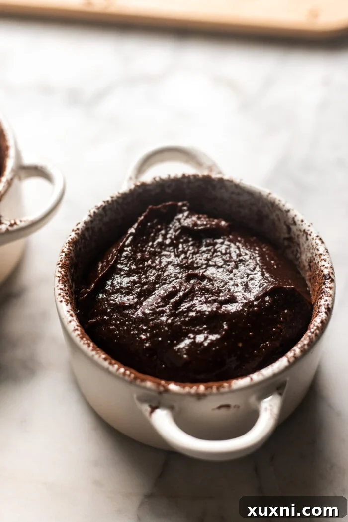Ramekin filled with batter and chocolate square, ready for the oven.