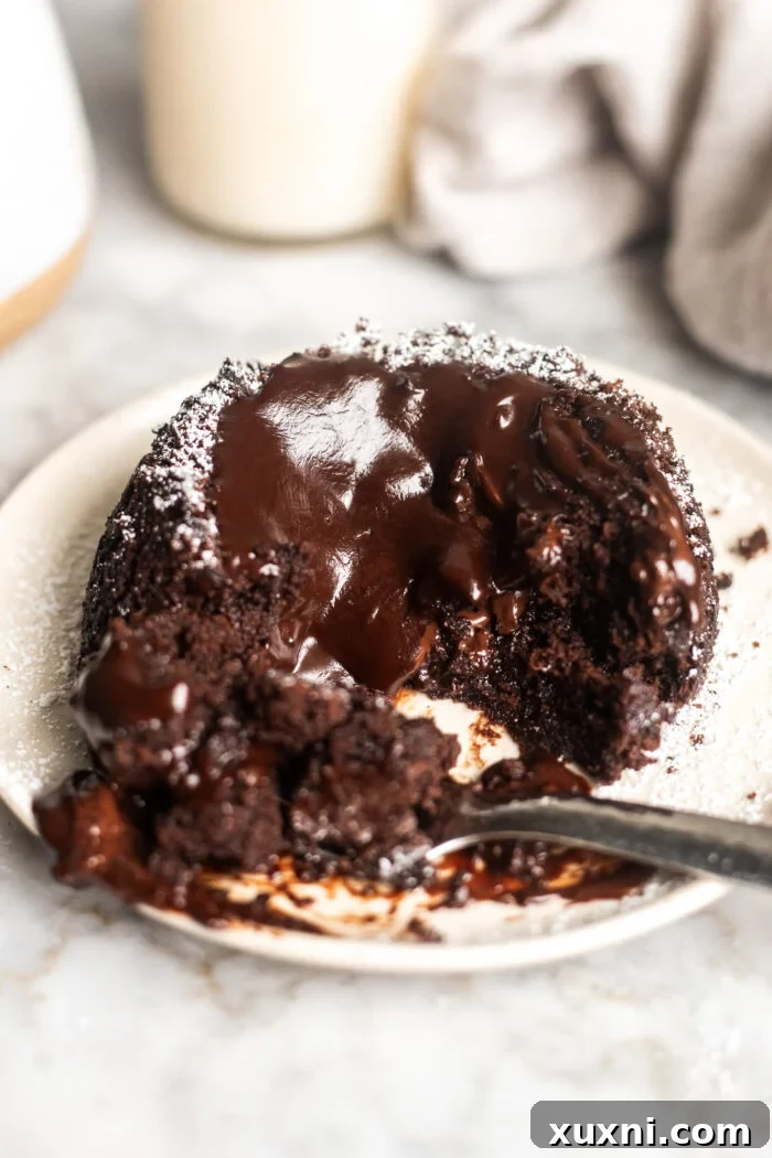A vegan lava cake on a plate with a spoon, highlighting its warm, soft center.
