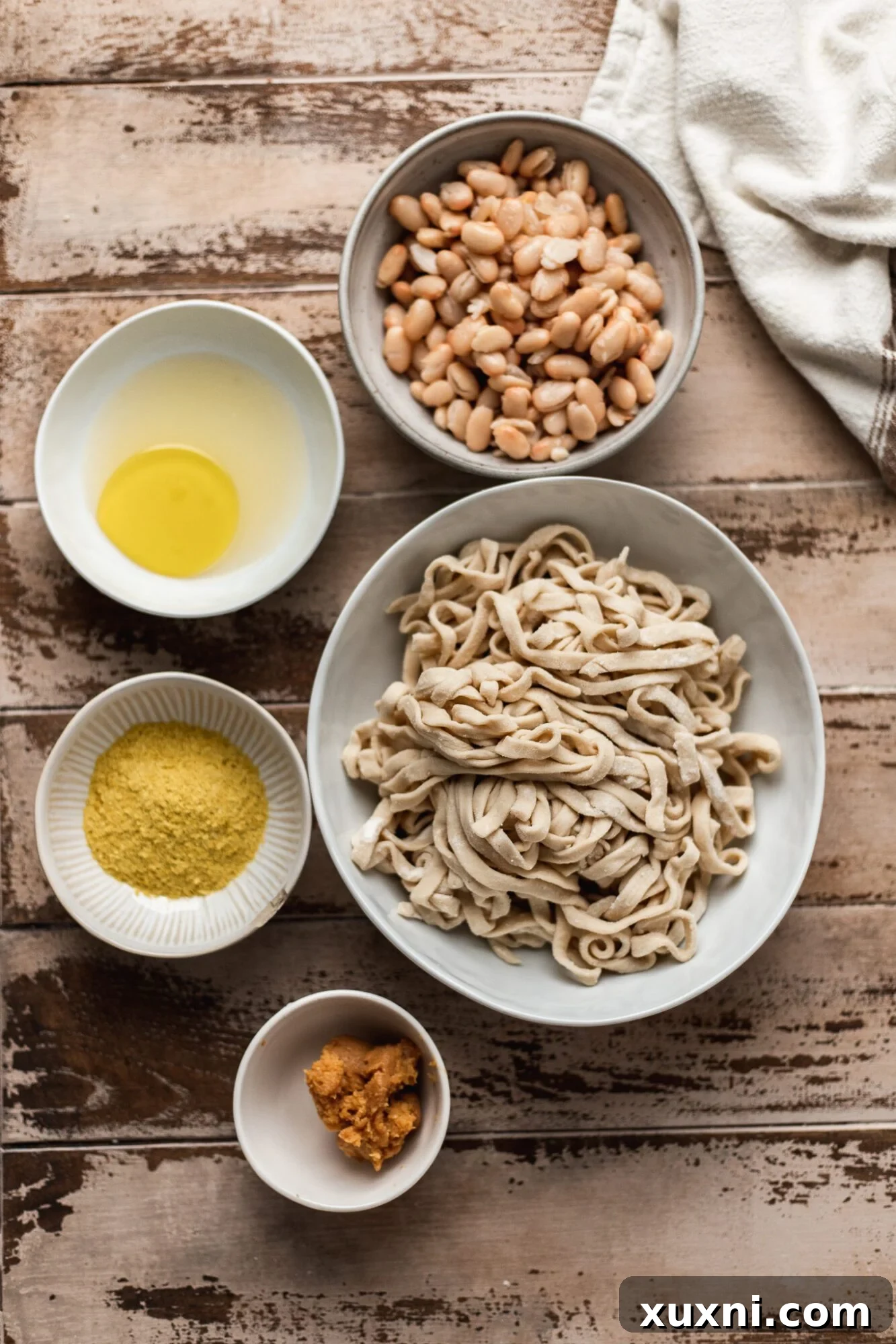 Unbelievably Creamy Nut-Free Vegan Cacio e Pepe 4 A flat lay image displaying all the simple ingredients for vegan cacio e pepe, including pasta, white beans, nutritional yeast, miso paste, and black pepper.