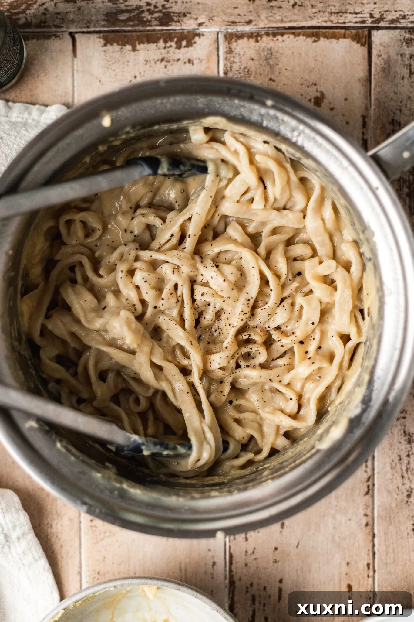 Unbelievably Creamy Nut-Free Vegan Cacio e Pepe 6 Pasta being tossed in a pan with the creamy vegan cacio e pepe sauce, showing it coating every strand.
