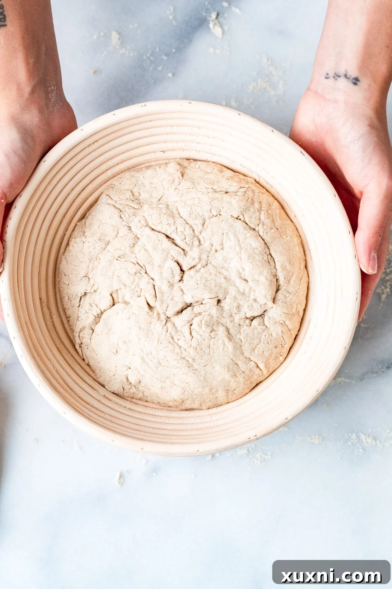 Gluten-free vegan dough placed seam-side up in a proofing basket, covered and ready for its second proof.