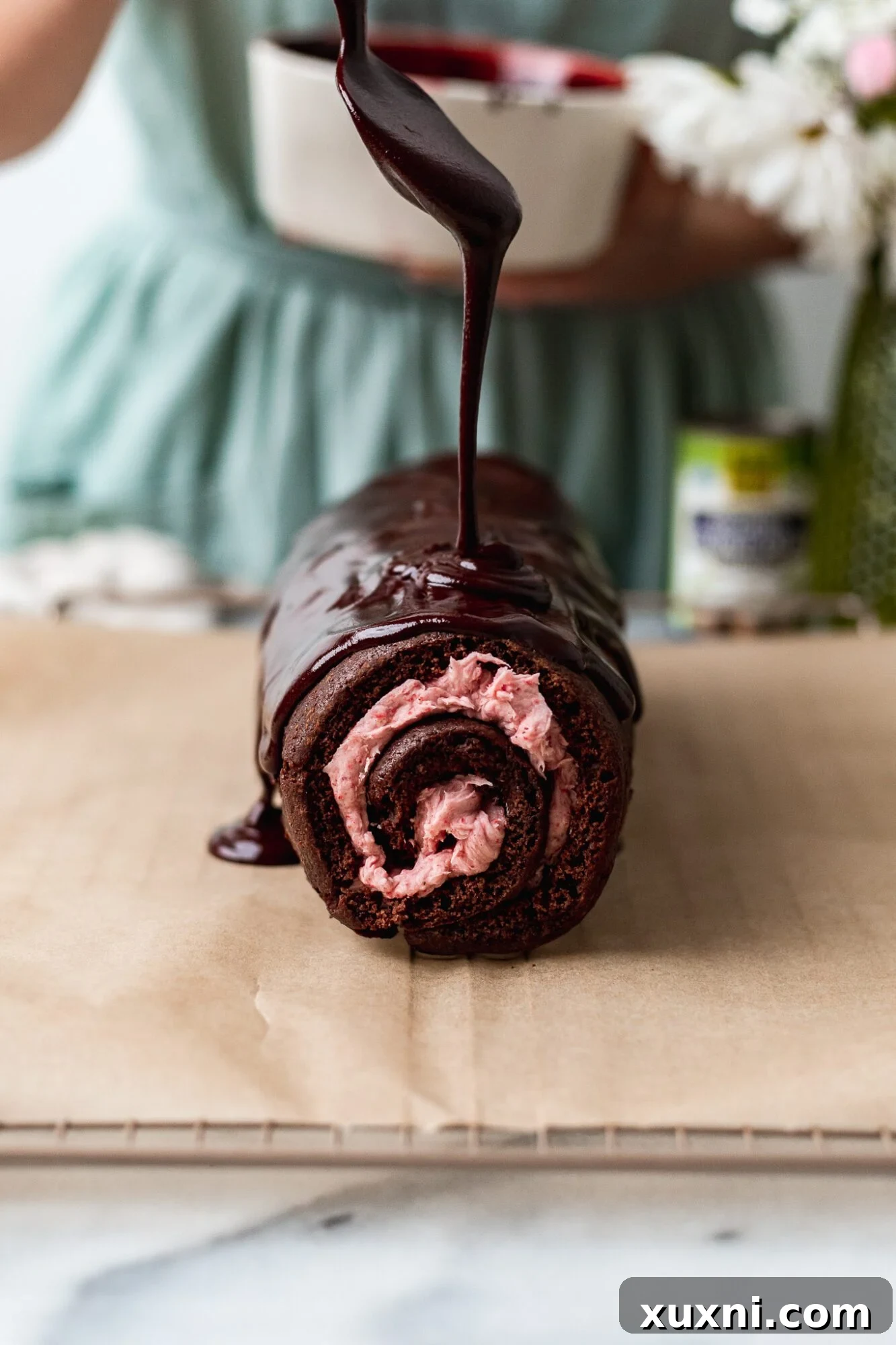 pouring ganache onto the chocolate Swiss roll