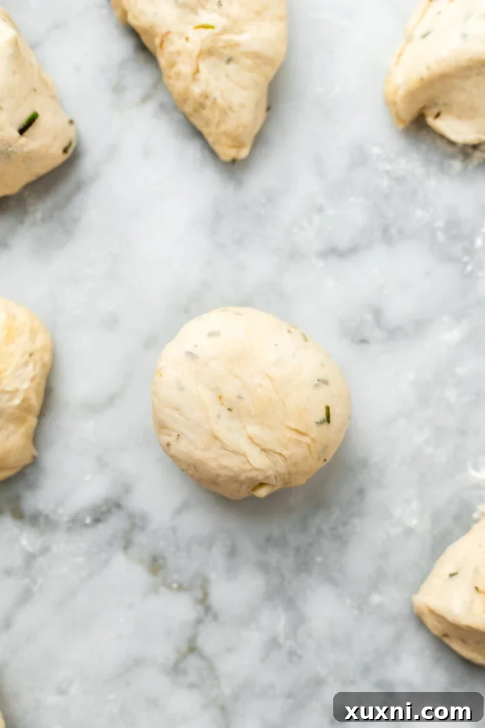 rolling a sealed dough ball to create a smooth dinner roll