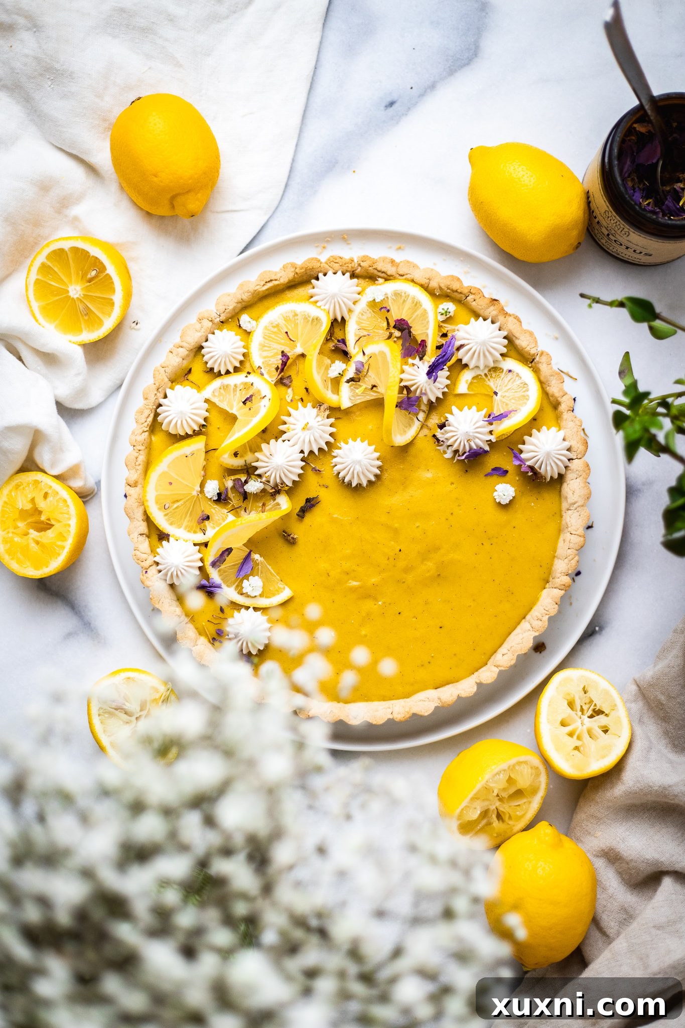 Decorated vegan lemon tart, garnished with fresh berries and edible petals.