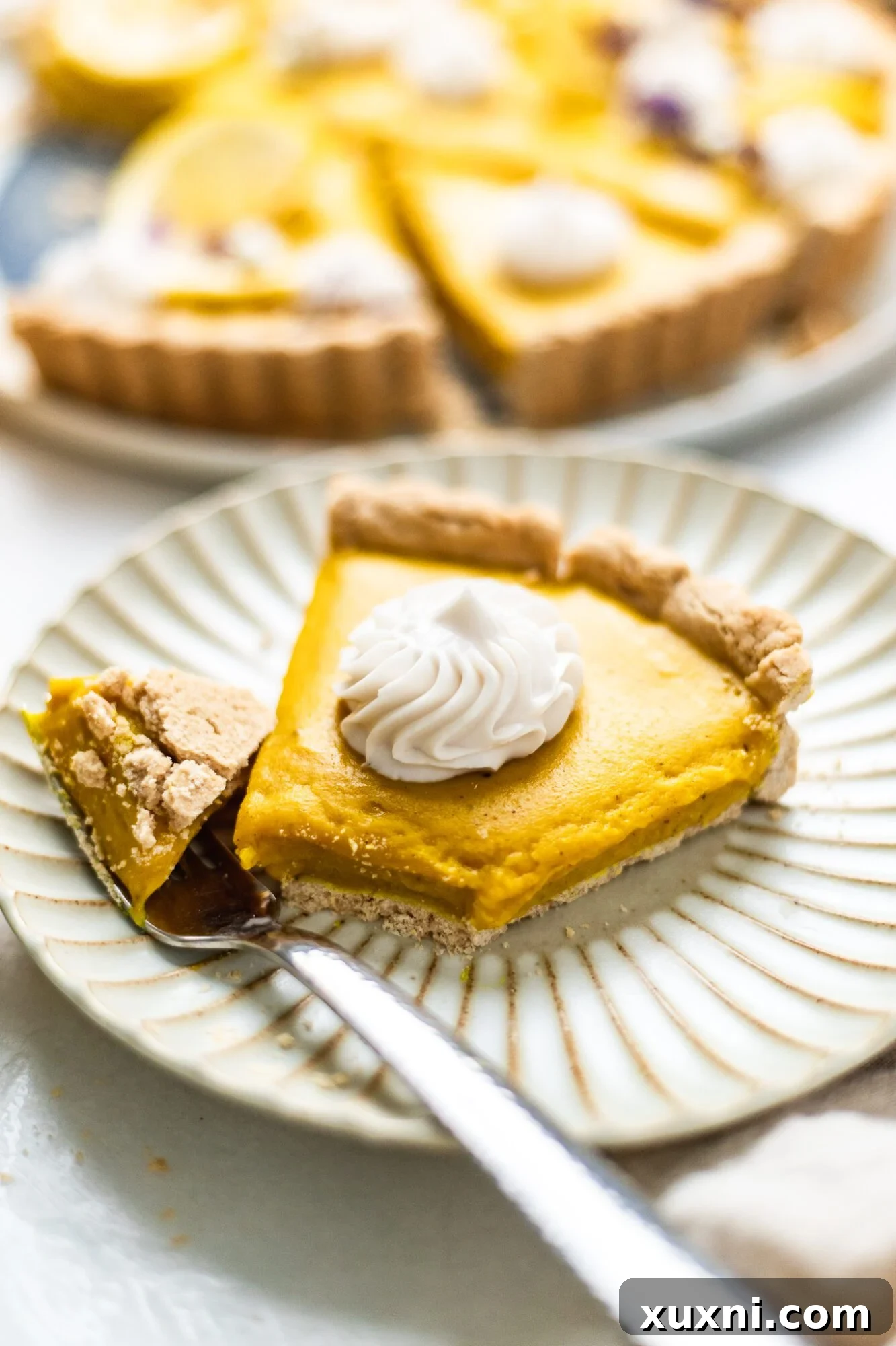 An almost entirely eaten slice of vegan lemon tart, showing a fork next to the plate.