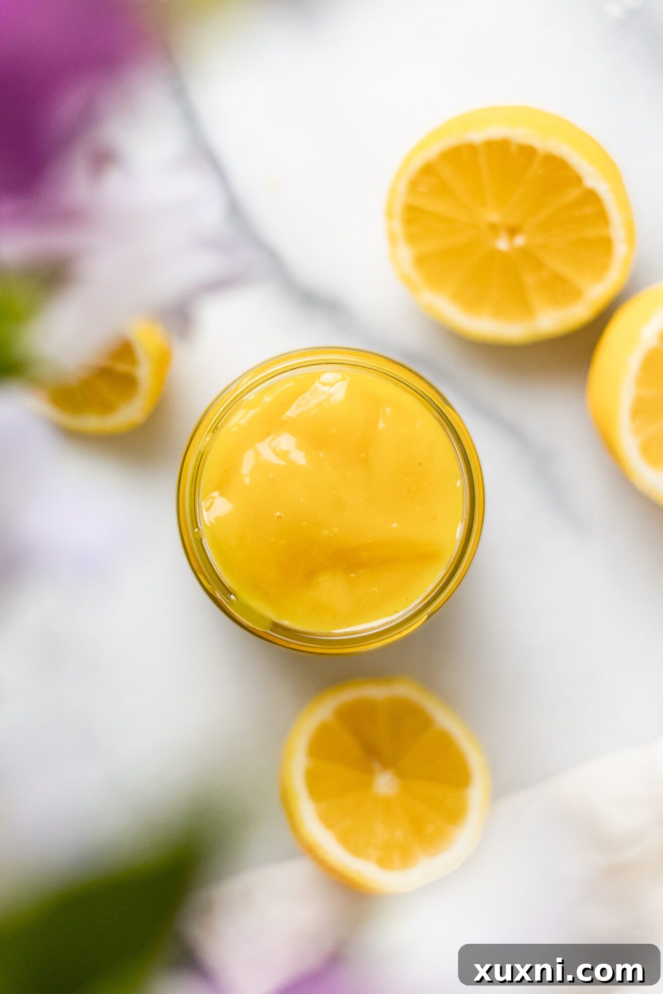 vegan lemon curd in a jar with lemons around it