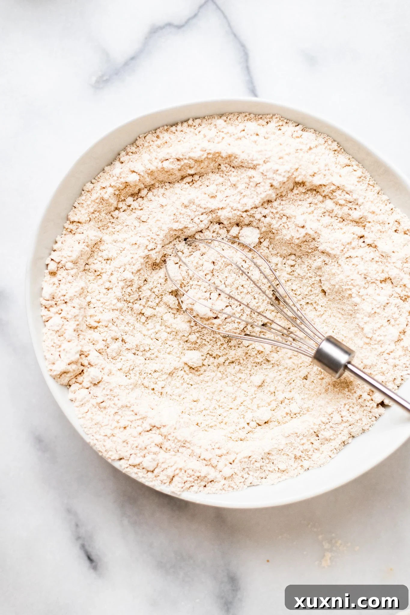 Whisking the dry ingredients for vegan lemon raspberry scones in a bowl.