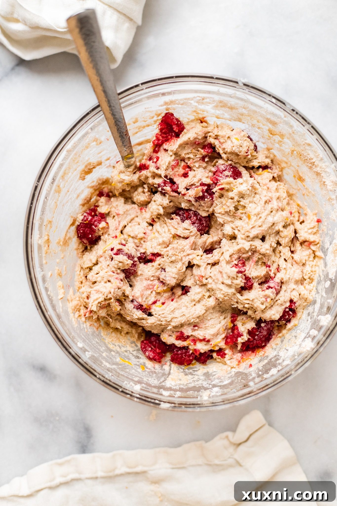 Mixing vegan buttermilk, raspberries, and lemon zest into scone dough.