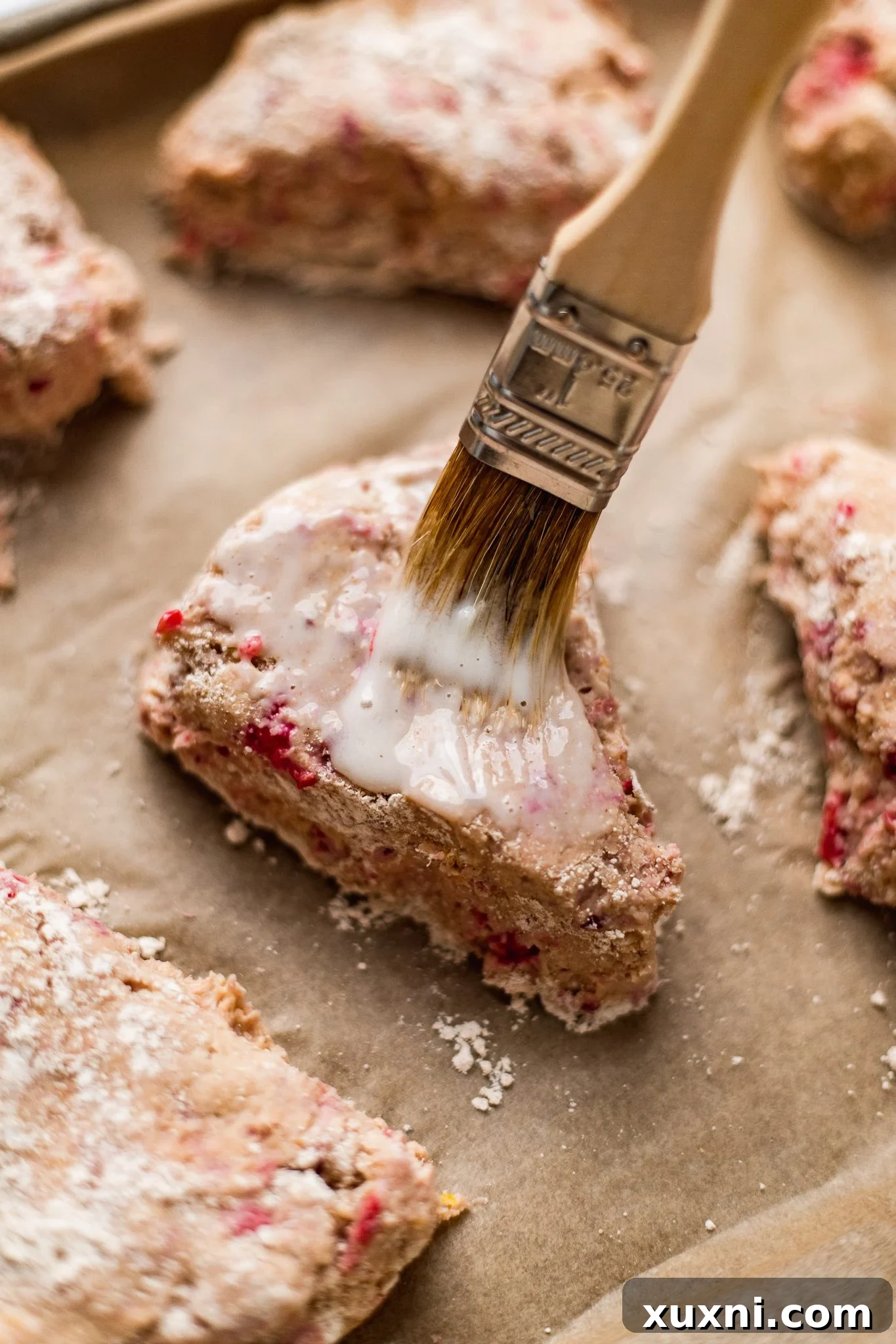 Brushing unbaked vegan scones with buttermilk and sprinkling with sugar.