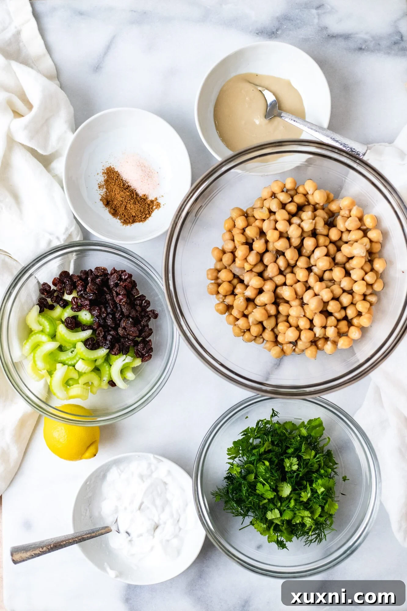 Plant Based Chickpea Tuna Salad 4 Assorted vegan chickpea tuna salad ingredients neatly arranged on a white marble surface, ready for preparation.