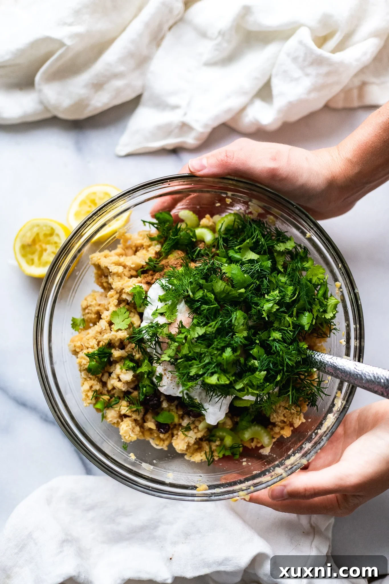 Plant Based Chickpea Tuna Salad 6 All ingredients for vegan tuna salad, including mashed chickpeas, herbs, and creamy dressing, added to a mixing bowl.