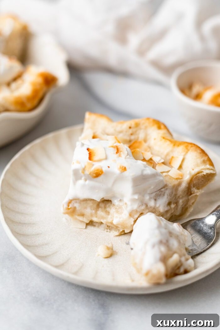 A slice of vegan coconut cream pie with a bite taken out, highlighting its rich layers and inviting texture.