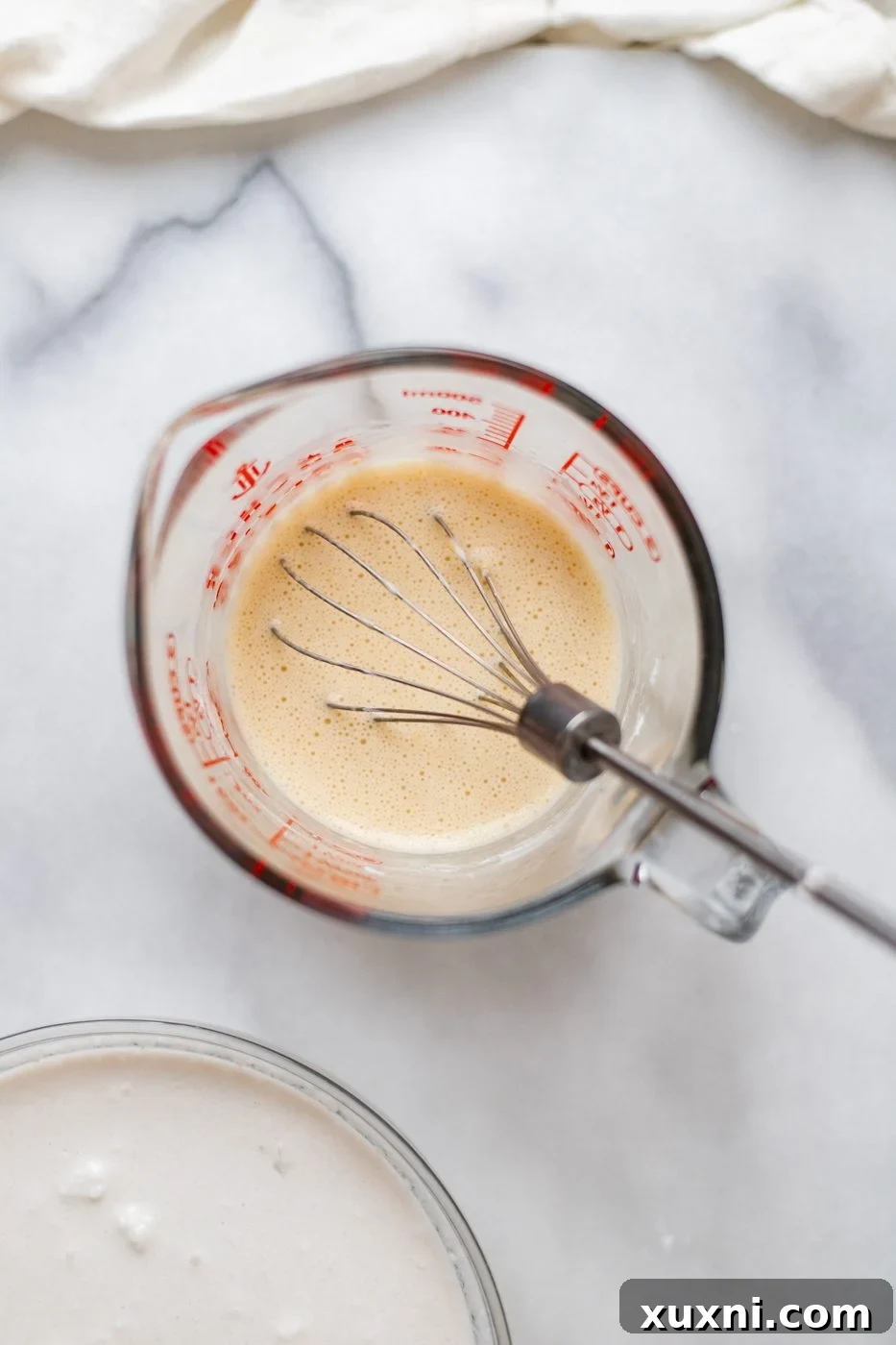 A jar containing a mixed solution of chickpea flour and aquafaba, showing the liquid's readiness to be used as an egg replacer.