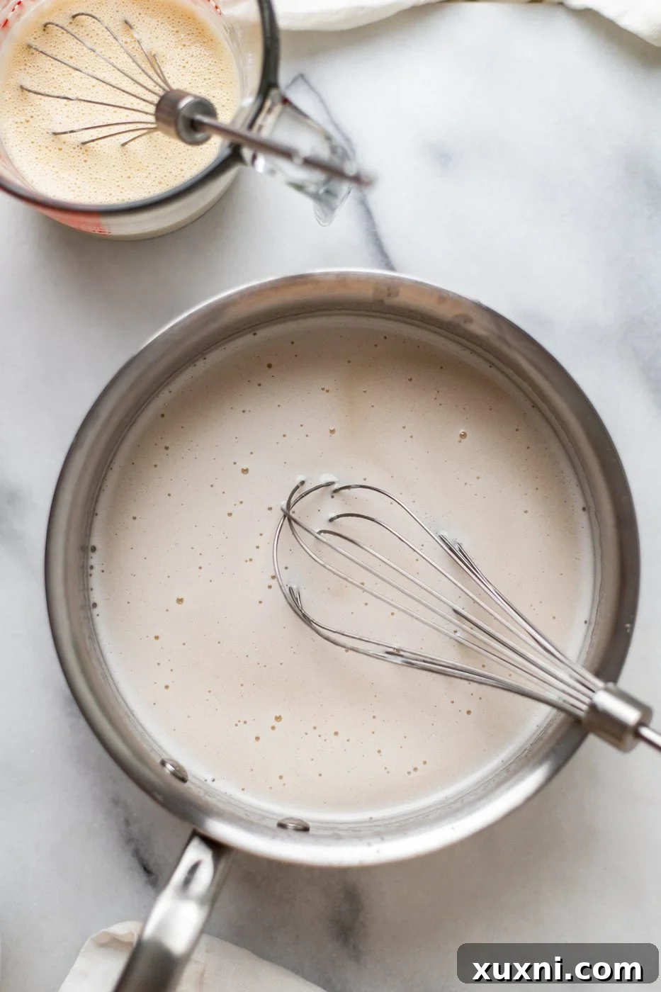 Coconut milk mixture gently heating in a saucepan on the stovetop, starting the process of making the pie filling.