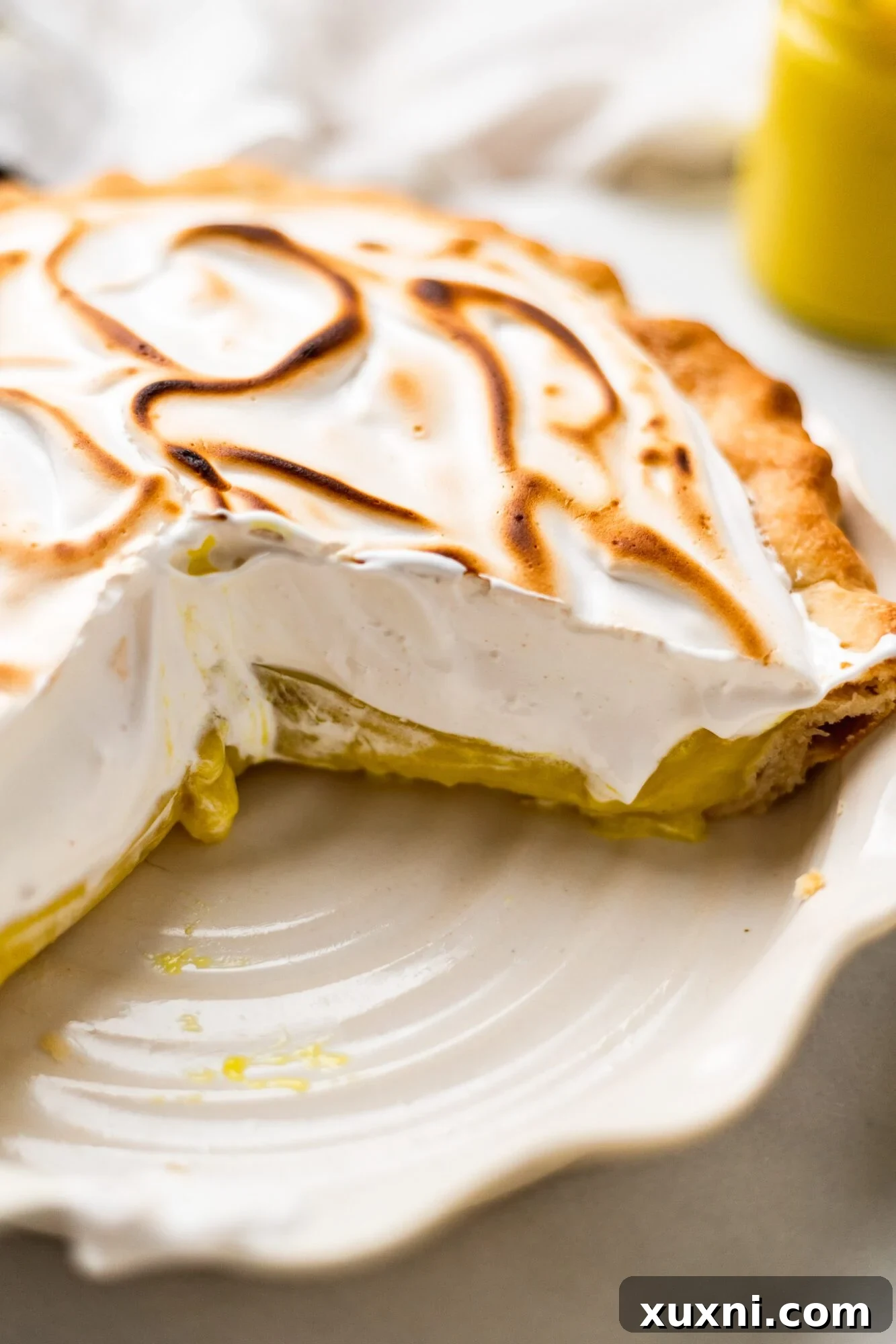 sliced lemon meringue pie - A perfectly cut slice of vegan lemon meringue pie, showcasing the layers of fluffy meringue, vibrant lemon curd, and golden crust.