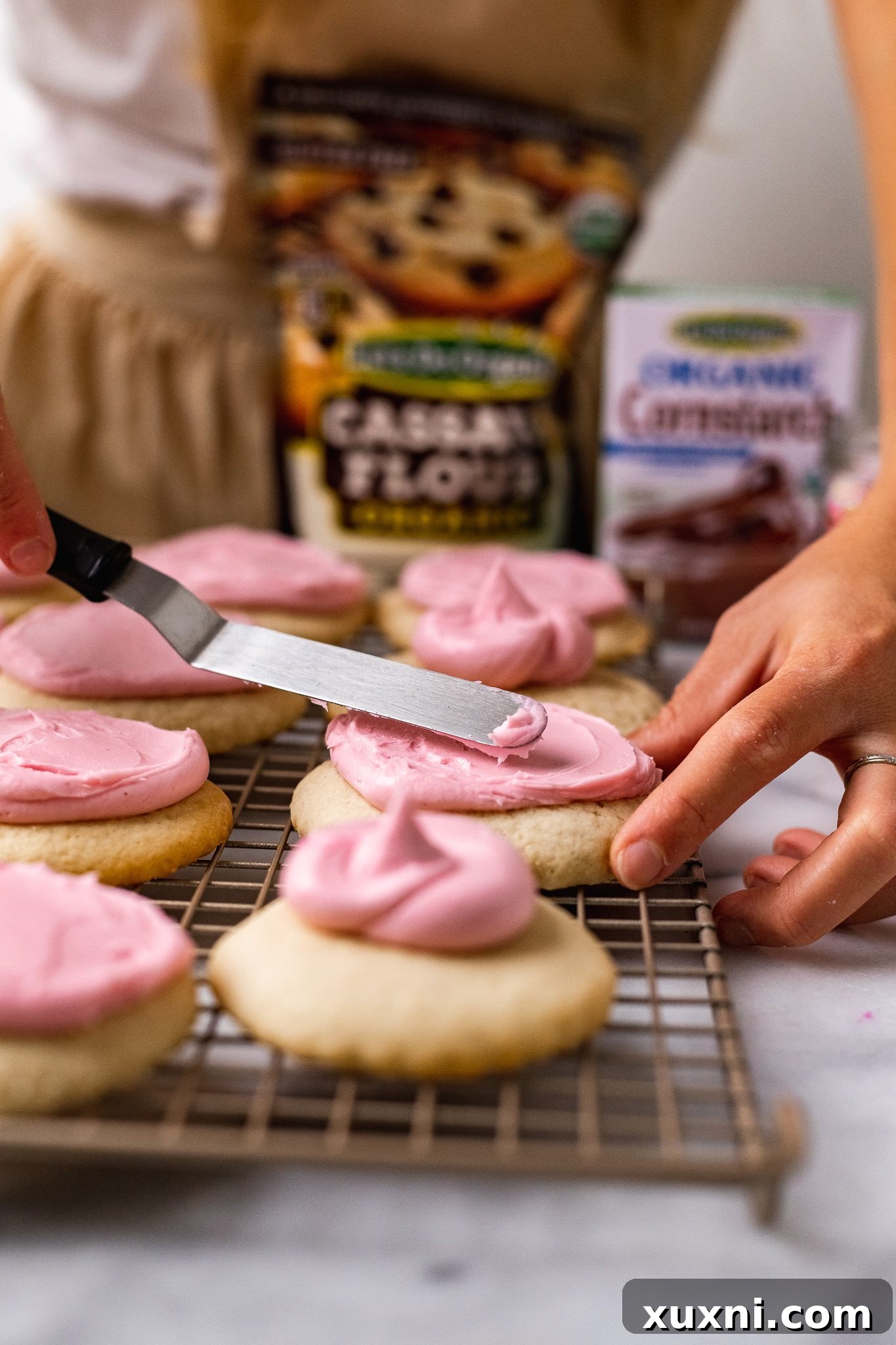 spreading the frosting onto cookies with an offset spatula