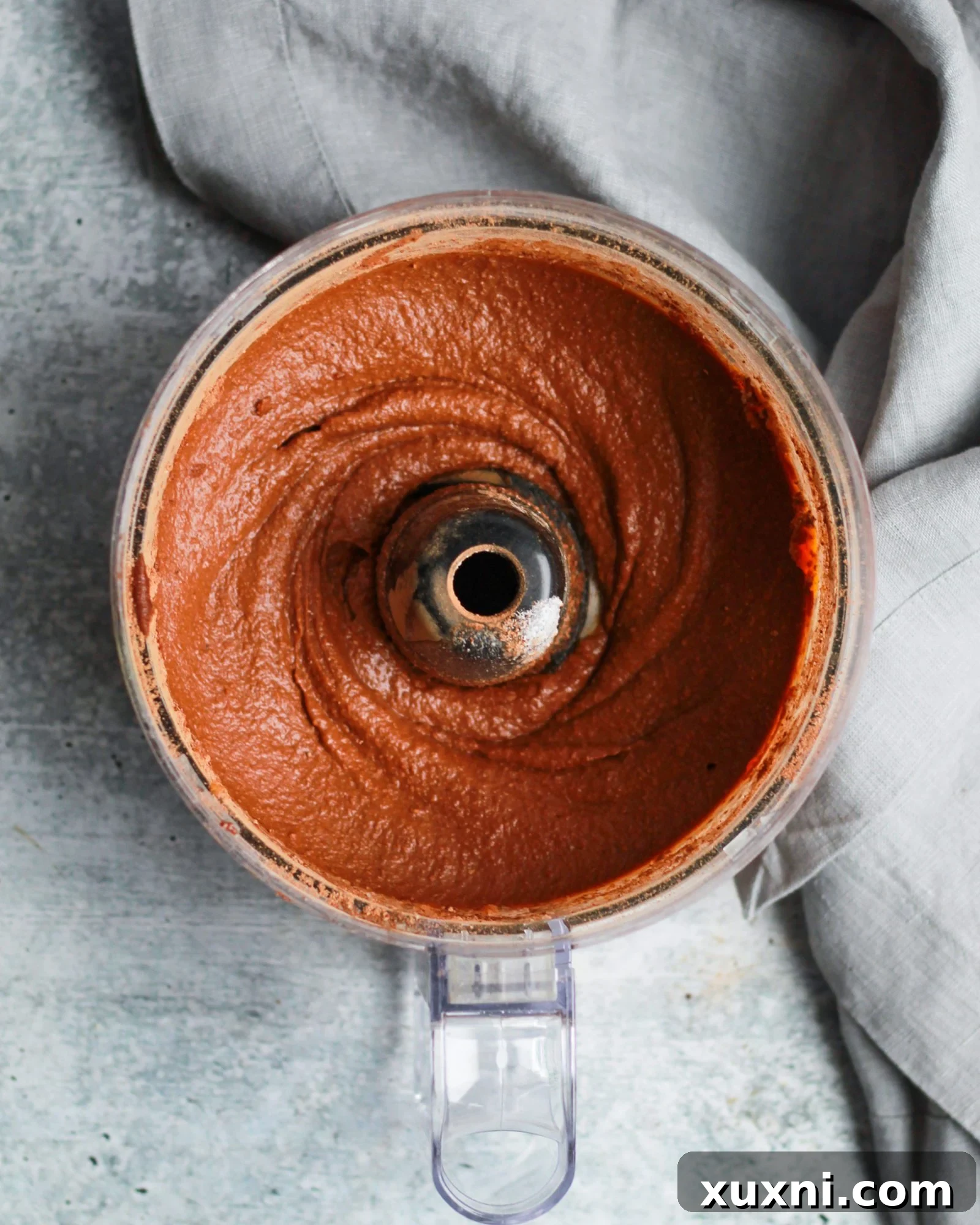 Food processor filled with creamy, dark brown healthy vegan Nutella brownie batter, ready for baking.