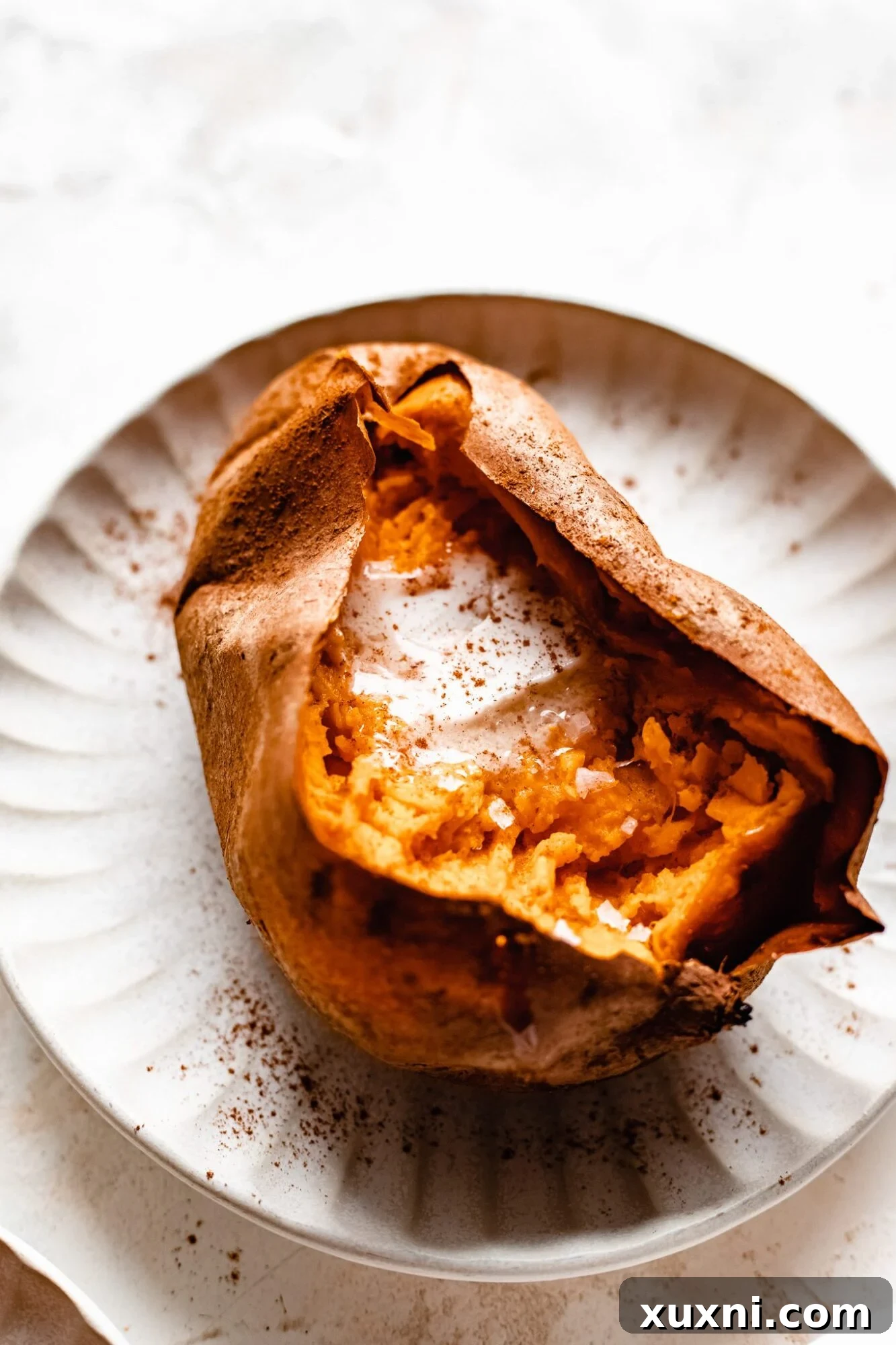 sliced sweet potato with pat of vegan butter on white plate