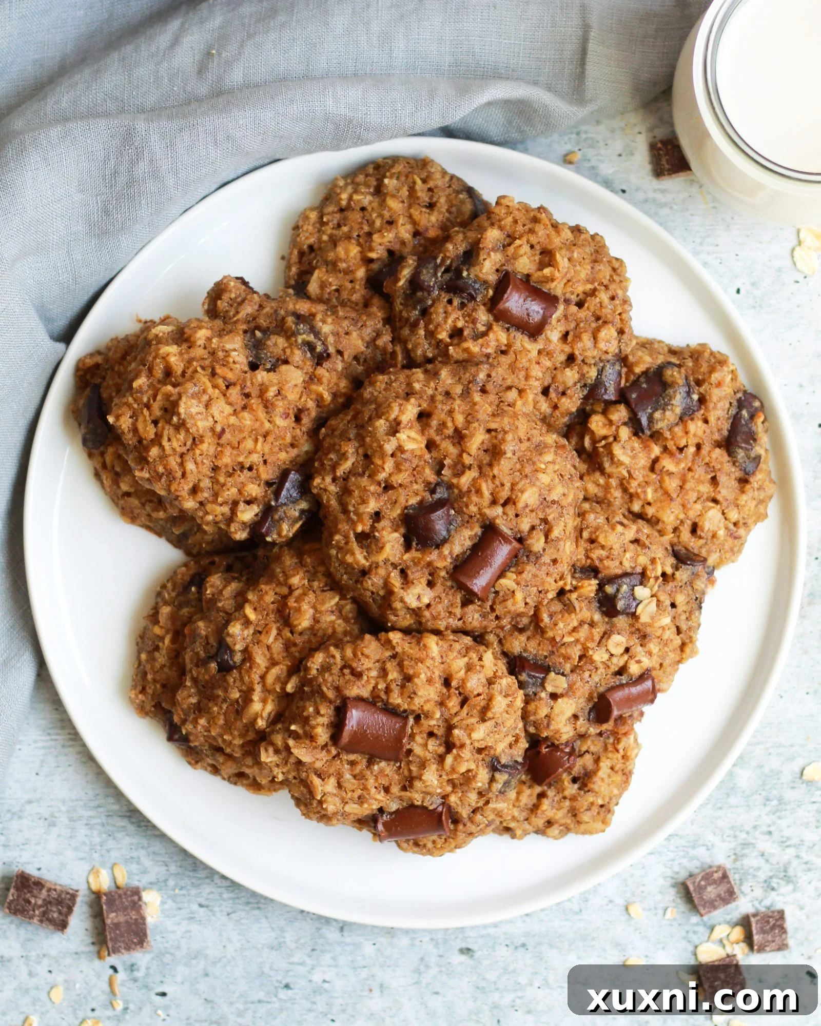 A plate of freshly baked healthy vegan oatmeal chocolate chip cookies with a refreshing glass of almond milk.