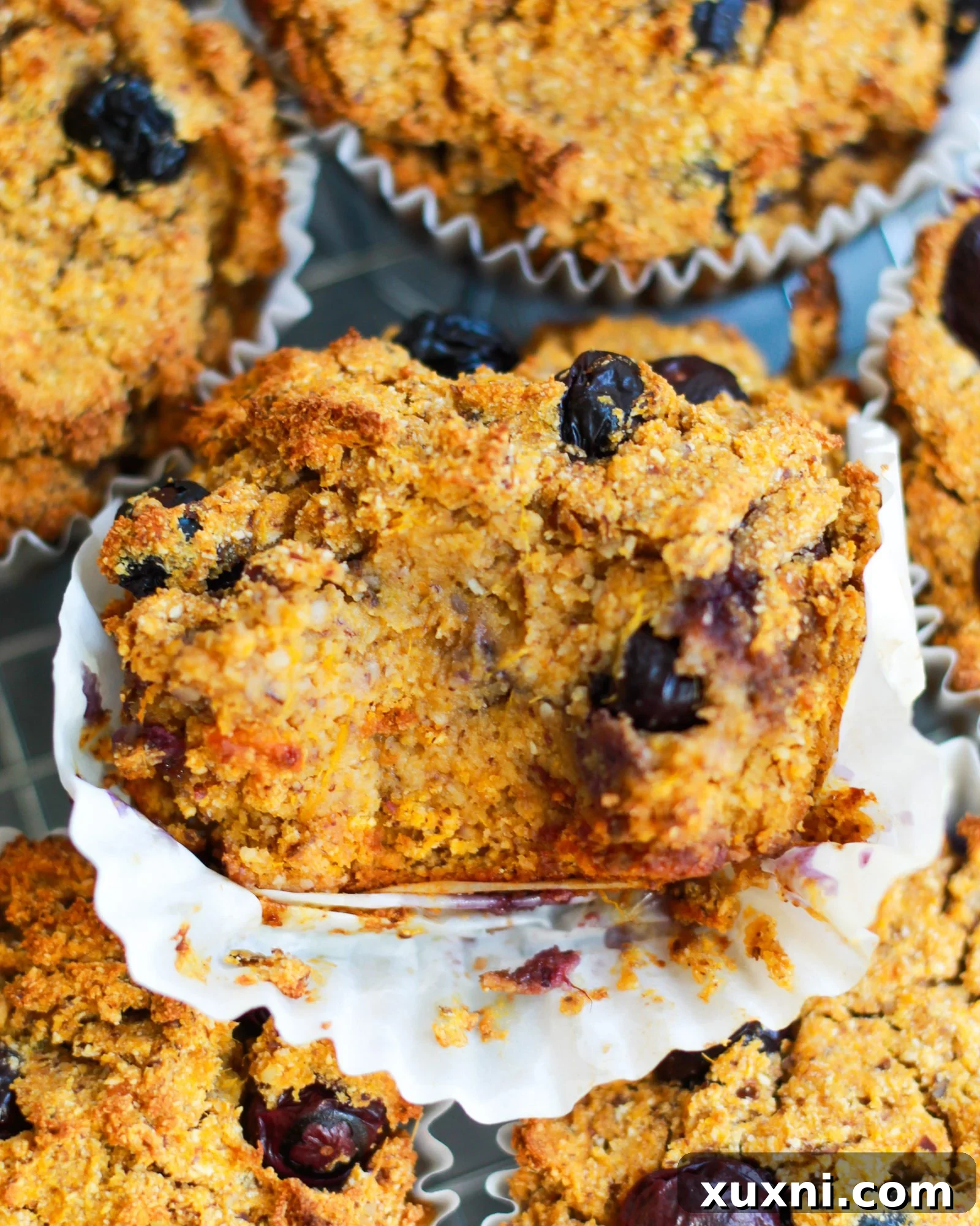 A close-up shot of a vegan blueberry muffin, with a bite taken out, revealing its fluffy interior and abundance of blueberries.