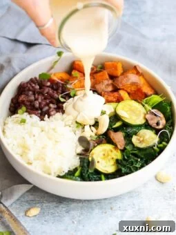3/4 shot of macrobiotic bowl with tahini dressing being poured on top