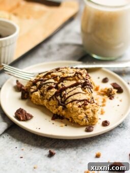 plate with chocolate chip scone and a glass of almond milk behind it
