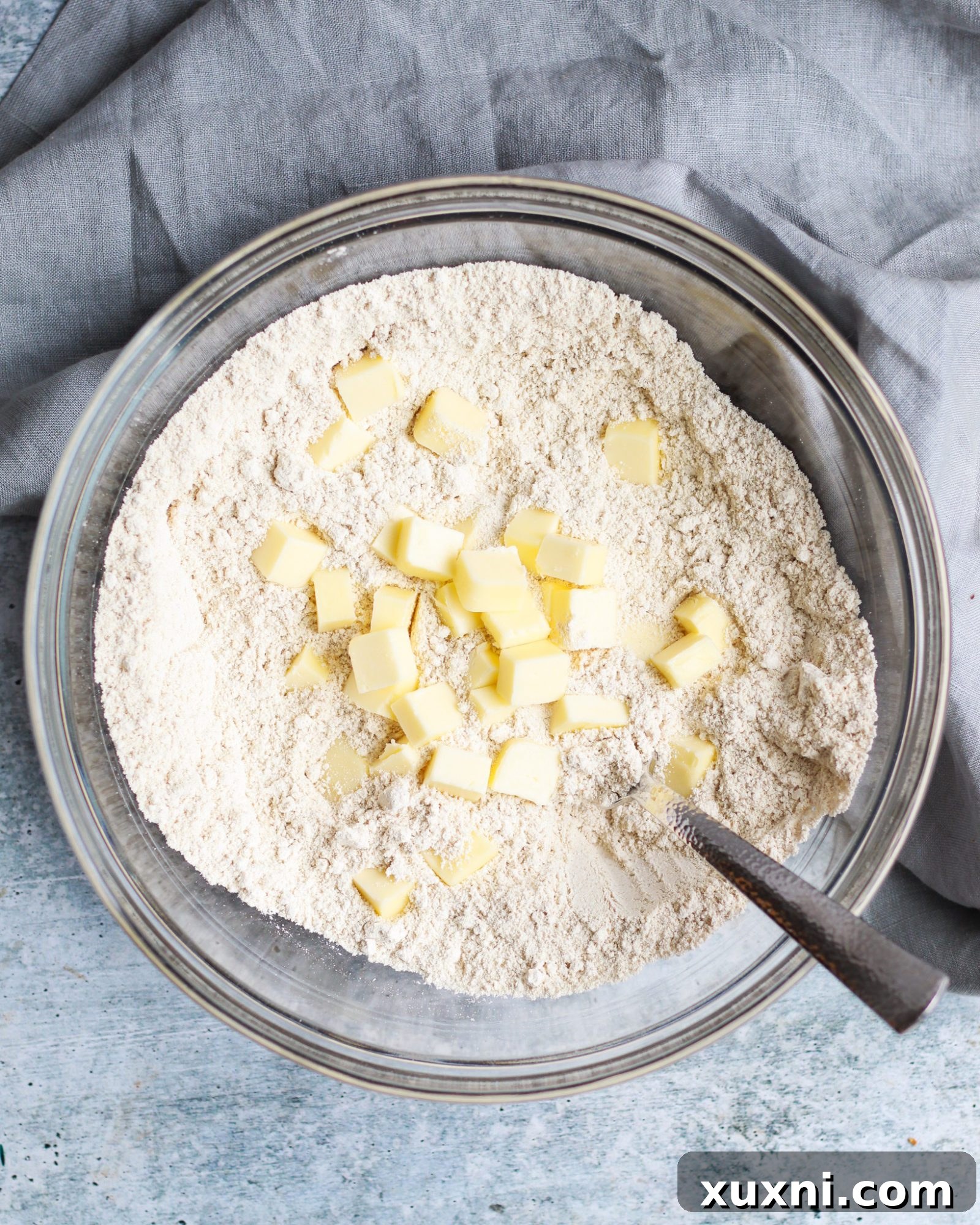 Bowl of oat and coconut flour with cubed cold butter, ready to be cut in for scone dough