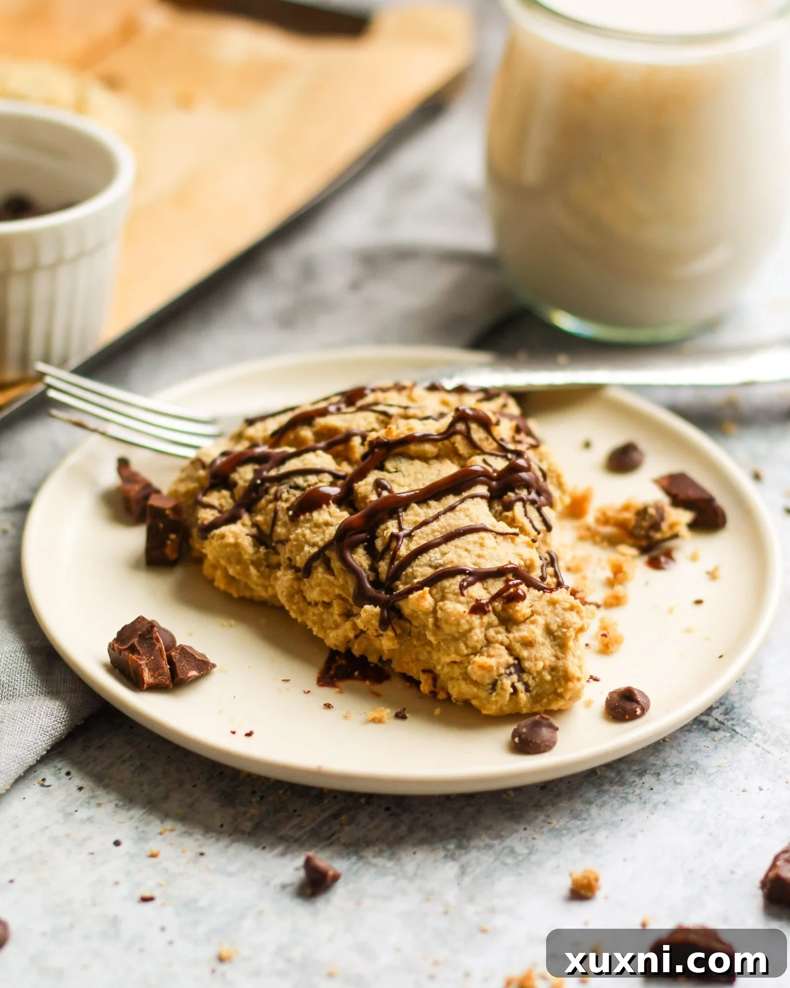 Baked chocolate chip scone on a plate with a glass of almond milk in the background