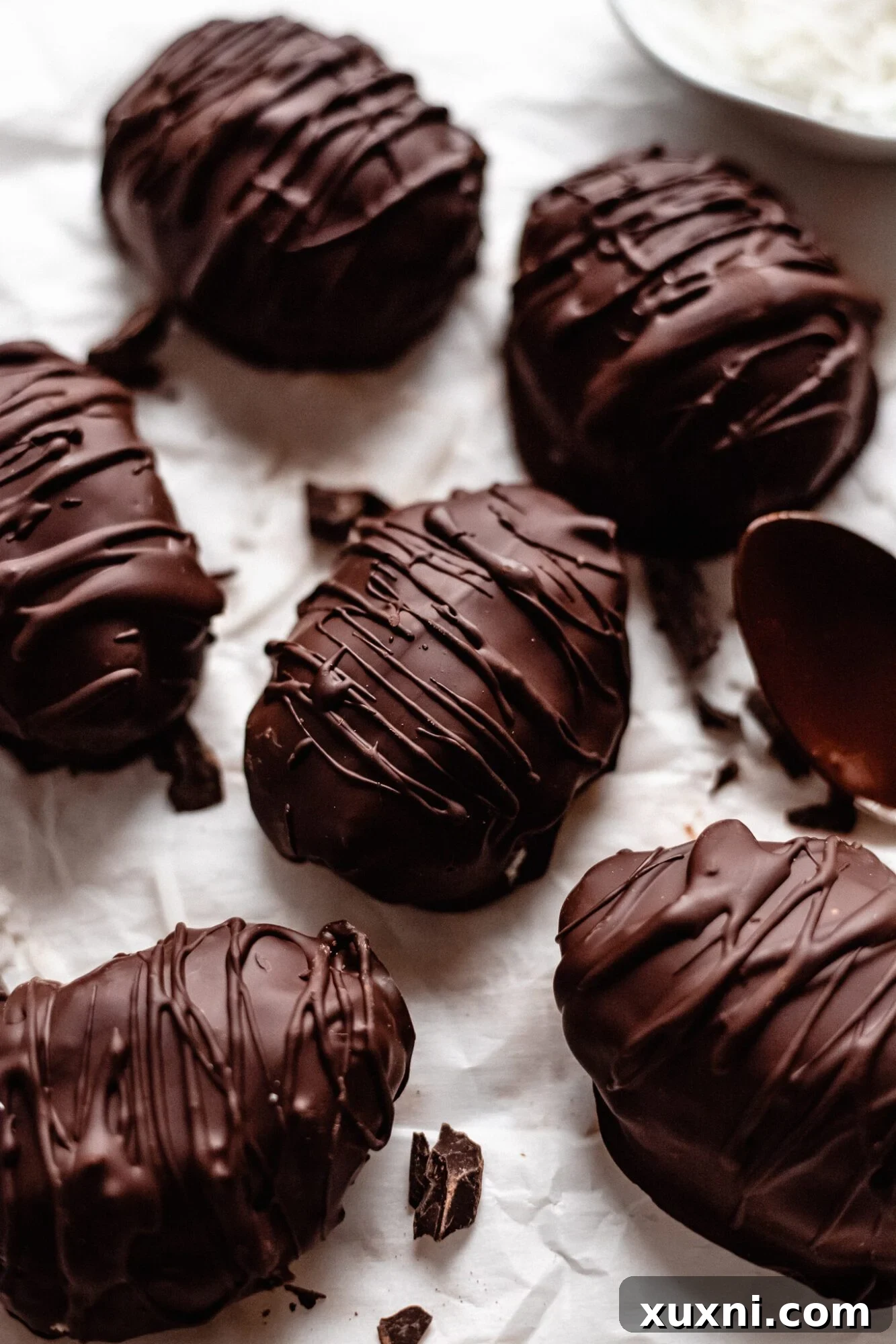 Freshly formed coconut cream eggs resting on parchment paper before their chocolate coating, highlighting their simple, natural form.