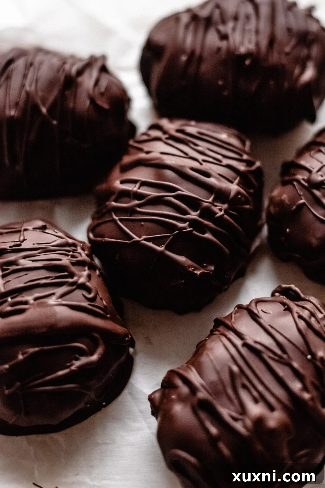 A generous pile of finished keto coconut cream eggs, glistening with a perfect chocolate shell, inviting a delicious indulgence.