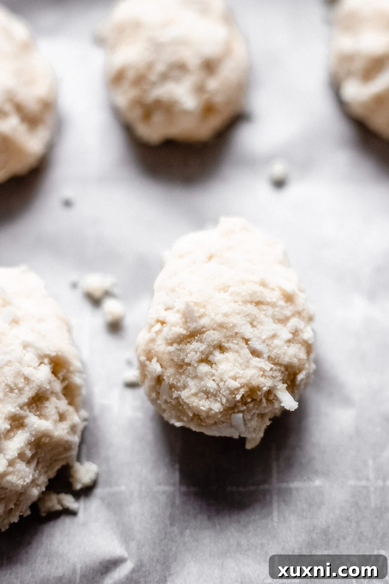 A selection of undipped coconut cream eggs, neatly lined on parchment paper, awaiting their final chocolate coating.