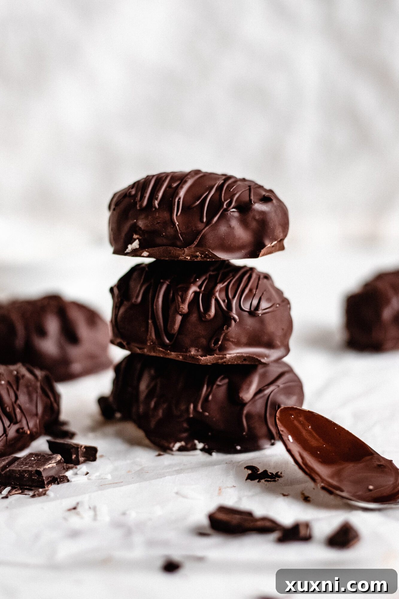 A stack of beautifully presented vegan coconut cream eggs, artfully drizzled with contrasting chocolate, a testament to their artisanal quality.