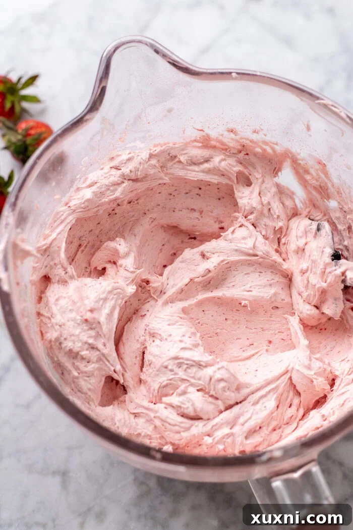 Fluffy, vibrant pink vegan strawberry buttercream in a bowl, showing its creamy texture.