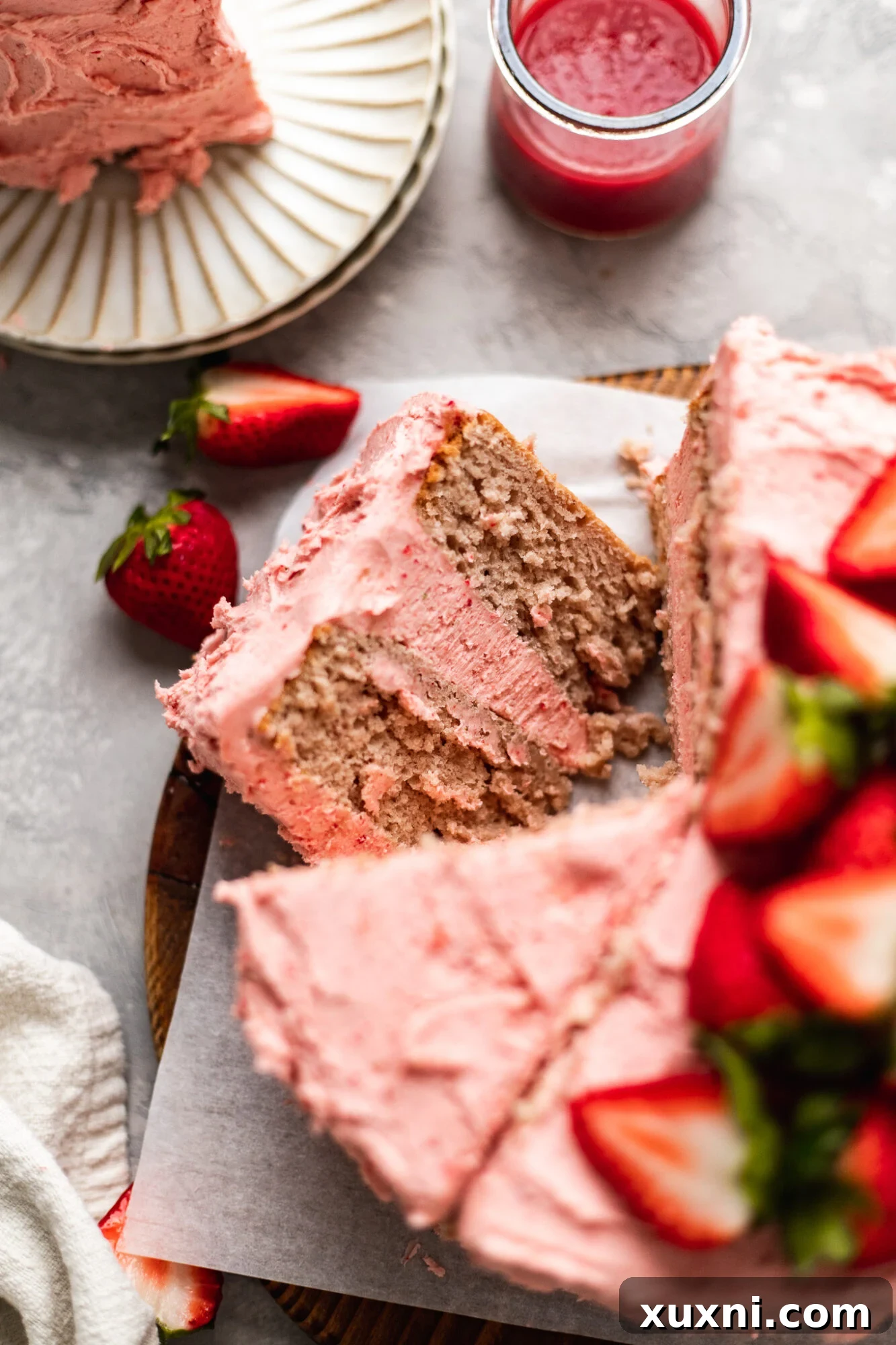 A perfectly sliced homemade vegan strawberry cake, revealing its beautiful interior and creamy frosting.