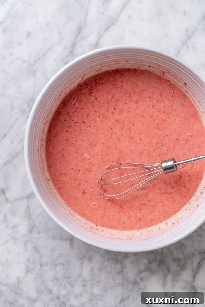 Bowl filled with smooth, pink strawberry cake batter, showing the perfect consistency.
