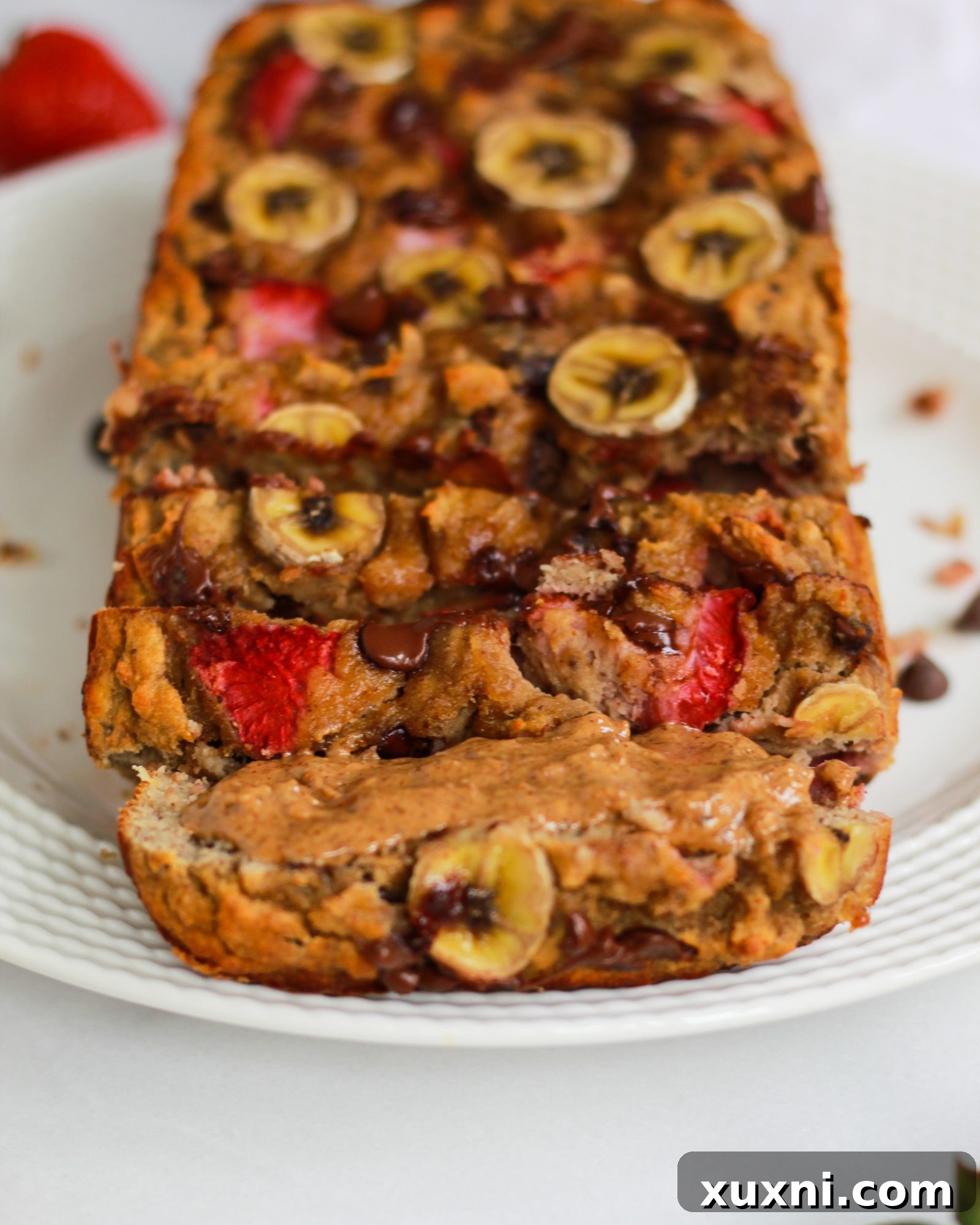A close-up view of a perfectly baked and sliced strawberry banana bread loaf, revealing its inviting texture.