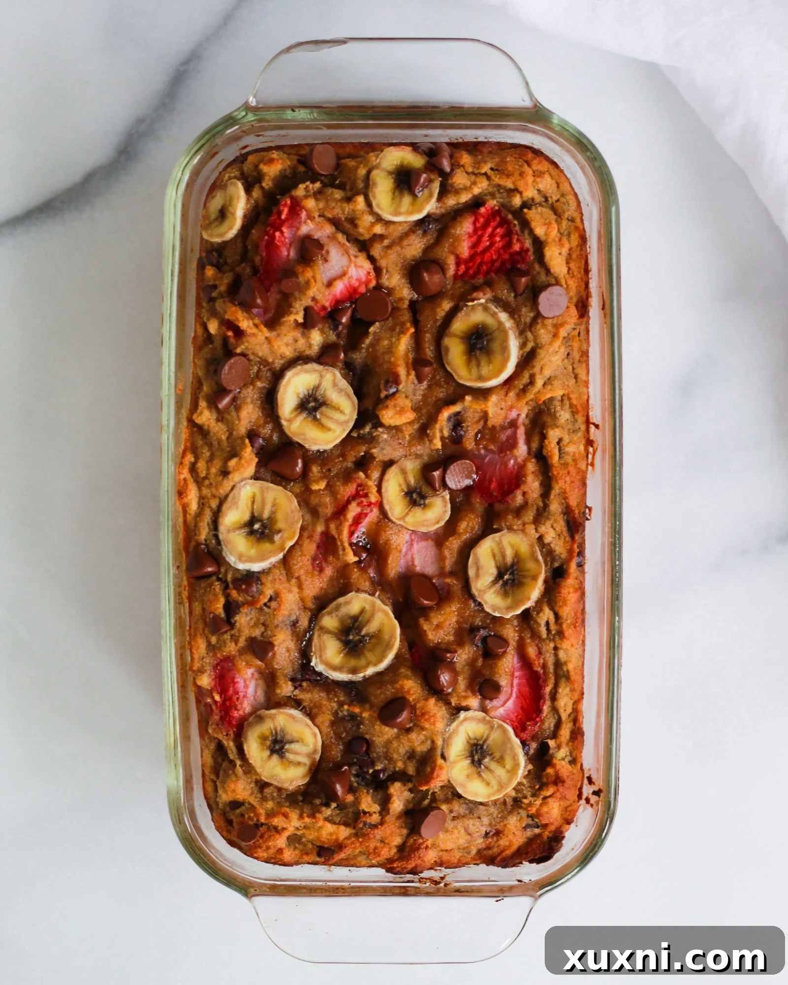 A beautifully baked Paleo strawberry banana bread cooling in a rustic loaf pan.