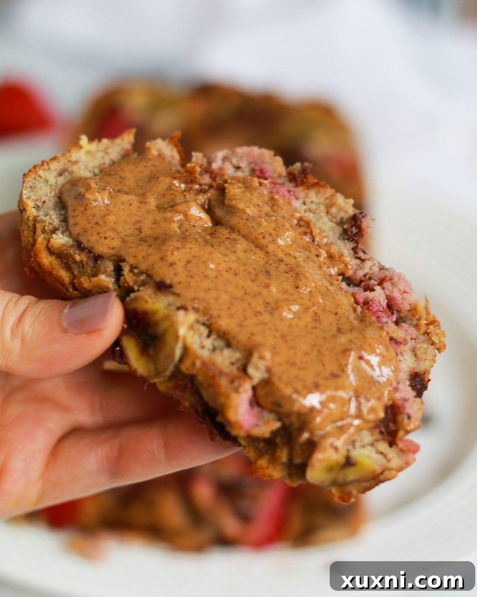 An inviting close-up of a slice of strawberry banana bread with visible chocolate and fruit.