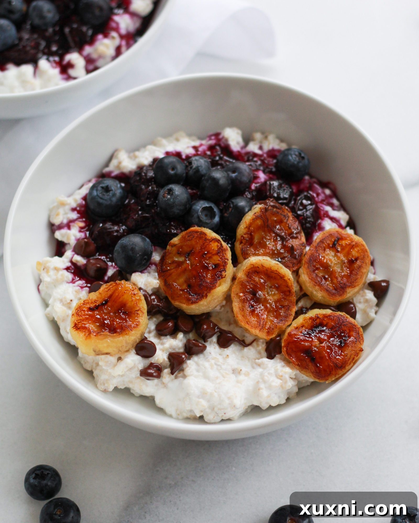 Bowl of oats generously topped with banana and fresh blueberries
