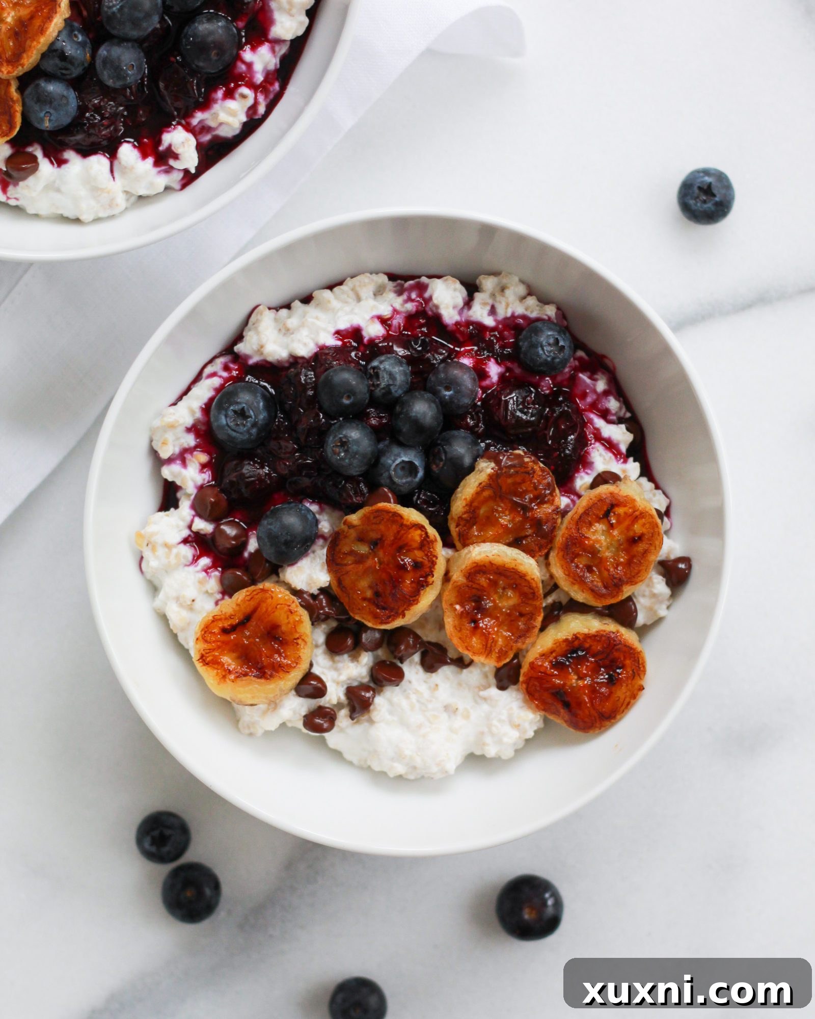 Plain oatmeal base topped with fresh banana slices and blueberries