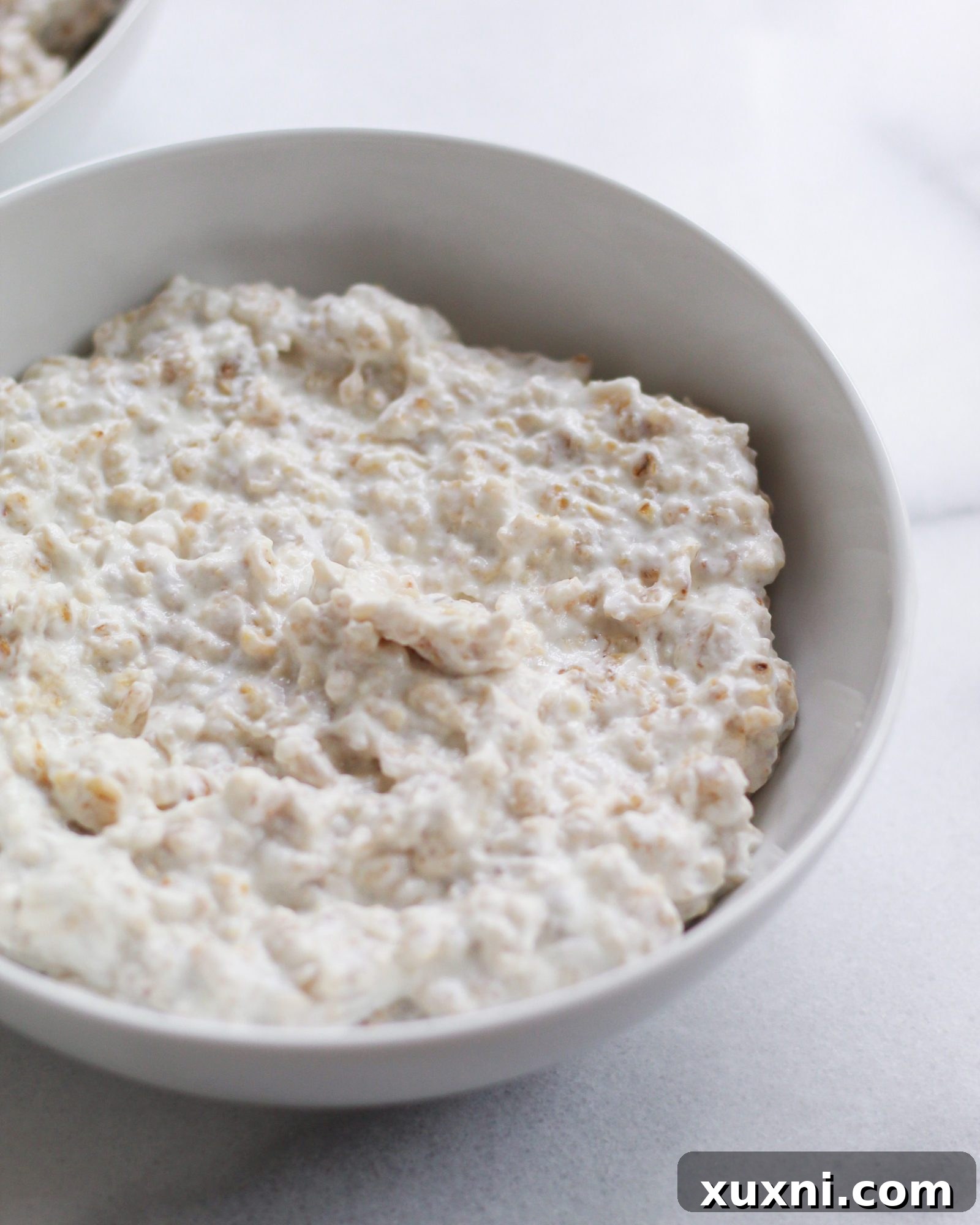 A white bowl containing plain, freshly made basic oatmeal
